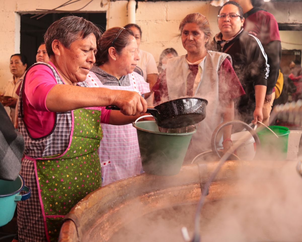 Mulheres servindo sopa numa cozinha comunitária