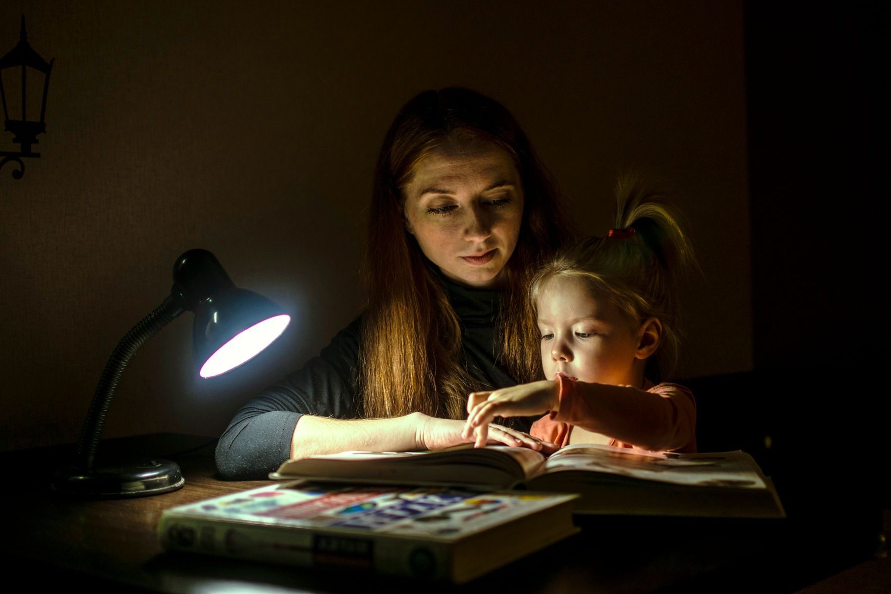 Mãe e filha lendo juntas sob a luz de um abajur